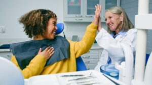 A dentist is pointing to a 3D model of a jaw with bone grafting, while consulting with a patient. No text on the image.